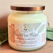 Jar of 'The Wise Sage' candle with a label on a wooden surface, surrounded by sage leaves.
