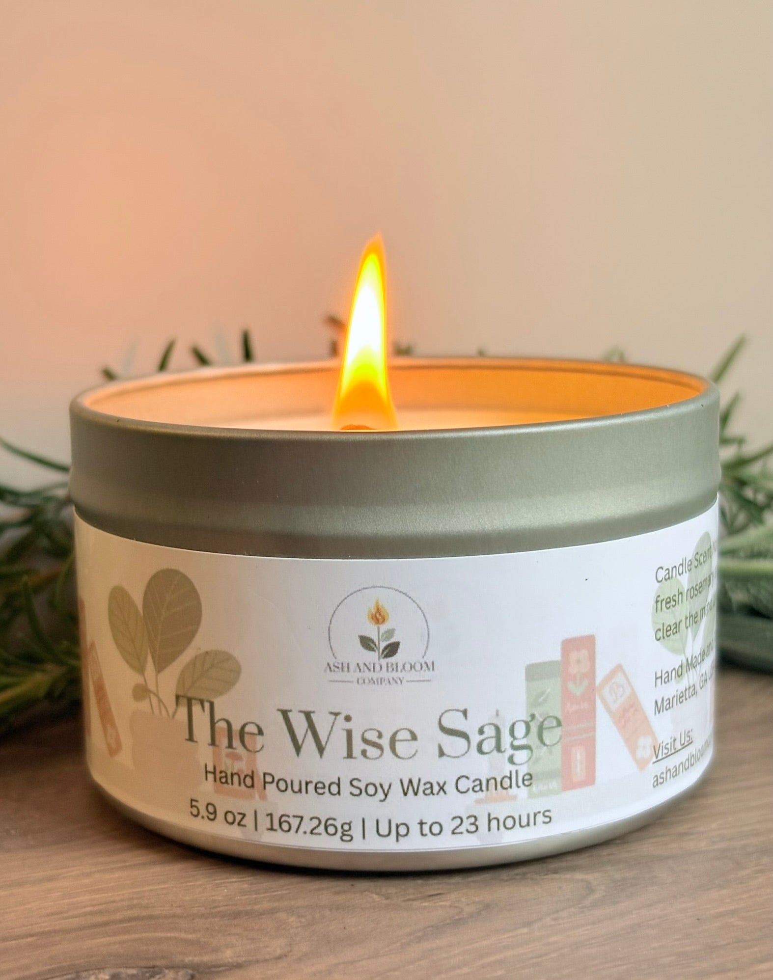 Candle in a tin labeled 'The Wise Sage' on a wooden surface with a blurred background