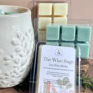 Packaged rosemary and sage soy wax melts labeled 'The Wise Sage' next to a white textured wax melter on a wooden surface.