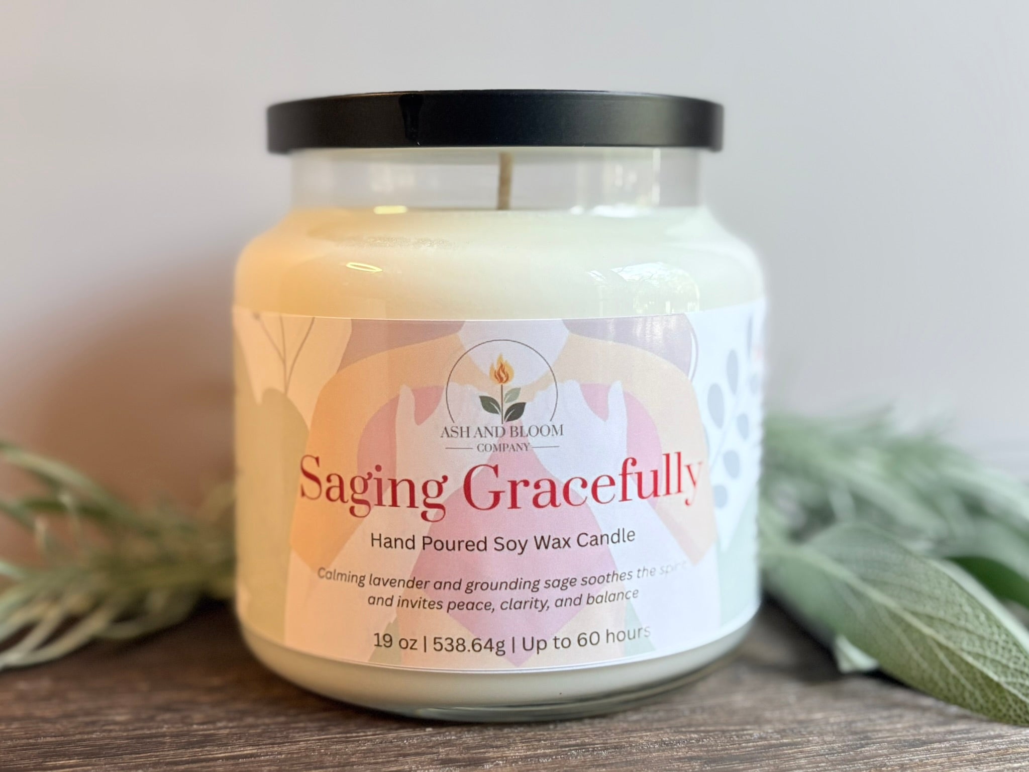 Lavender and Sage Candle jar labeled 'Saging Gracefully' with a plant in the background