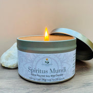 Nag champa scented candle in a tin labeled 'Spiritus Mundi' with a lit wick on a wooden surface.