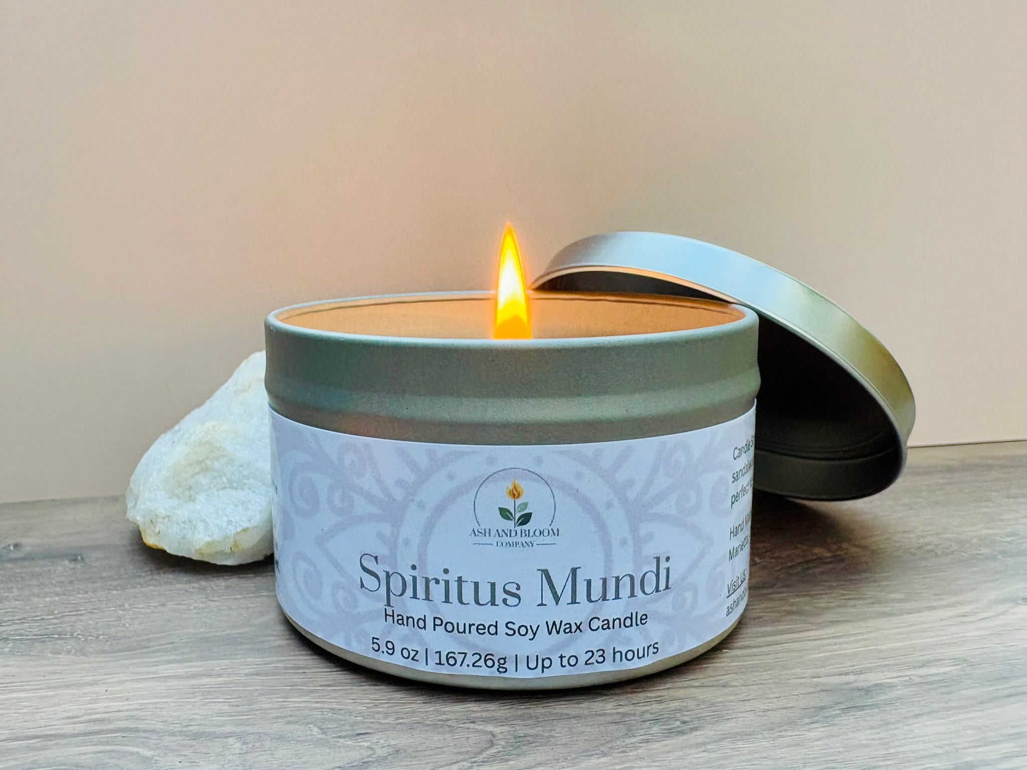 Nag champa scented candle in a tin labeled 'Spiritus Mundi' with a lit wick on a wooden surface.