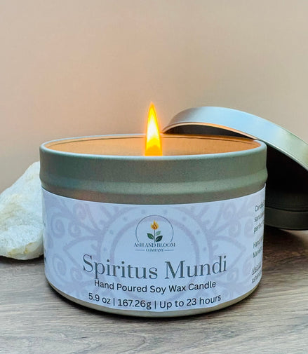 Nag champa scented candle in a tin labeled 'Spiritus Mundi' with a lit wick on a wooden surface.