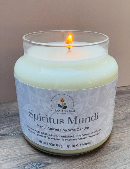 Nag champa candle in a glass jar labeled 'Spiritus Mundi' by Ashland Bloom on a wooden surface.