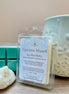 Nag Champa scented soy wax melts packaging with a candle and teal wax cubes on a wooden surface
