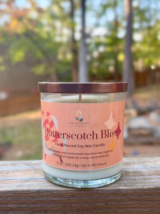 Butterscotch Bliss candle with a pink label on a wooden surface outdoors