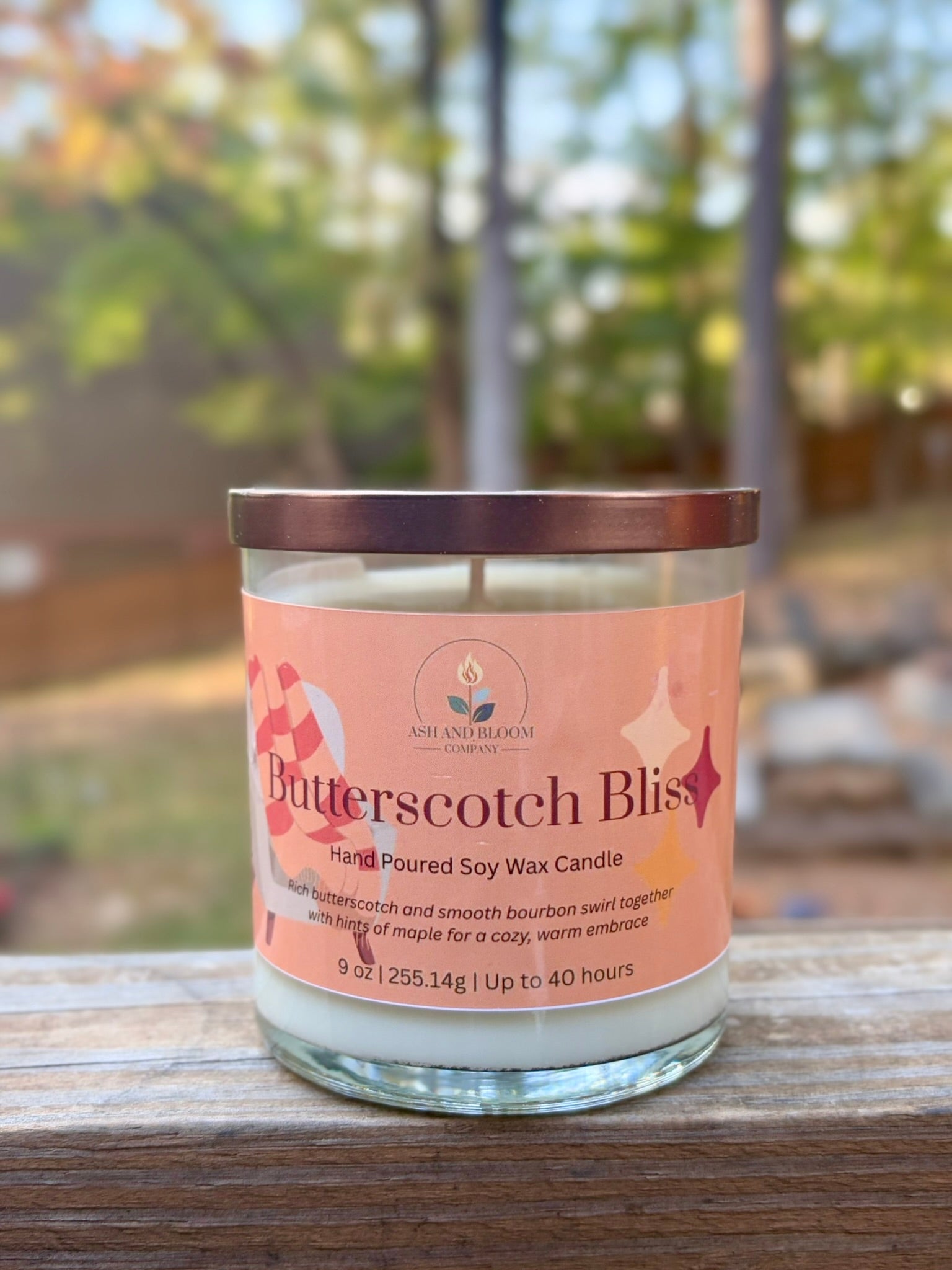 Butterscotch Bliss candle with a pink label on a wooden surface outdoors