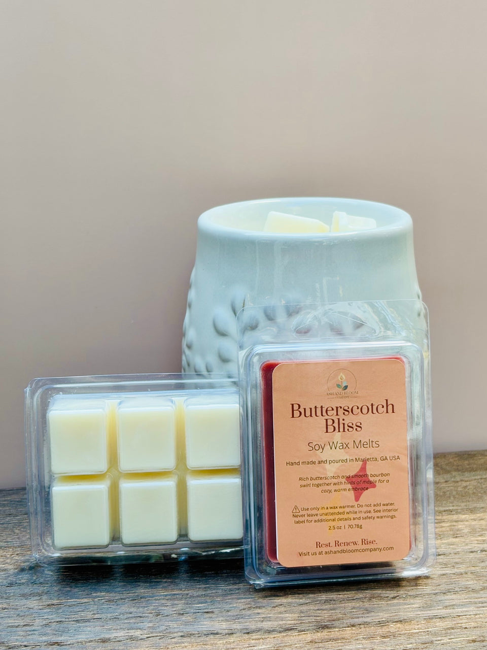 Butterscotch Bliss butterscotch and bourbon soy wax melts packaging with a wax warmer on a wooden surface.