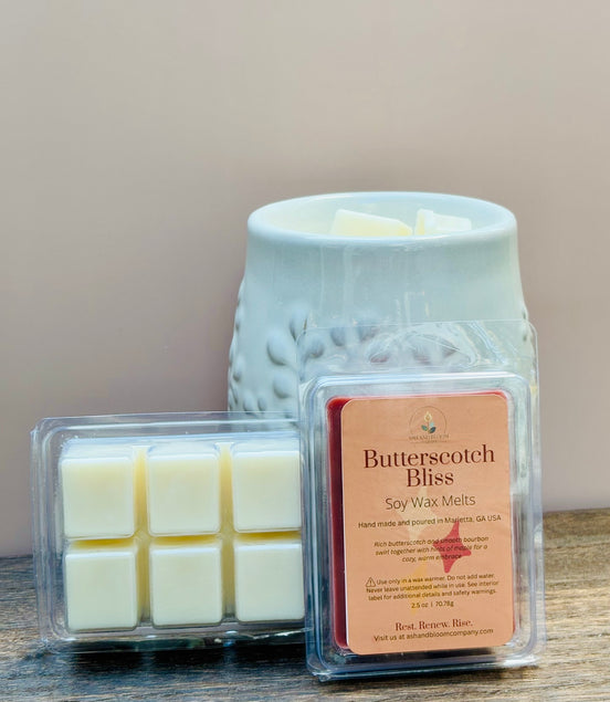 Butterscotch Bliss butterscotch and bourbon soy wax melts packaging with a wax warmer on a wooden surface.