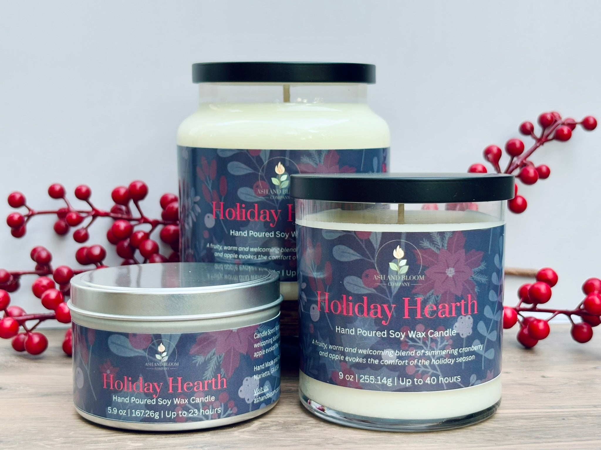 Three cranberry and apple 'Holiday Hearth' candles with red berries on a light background