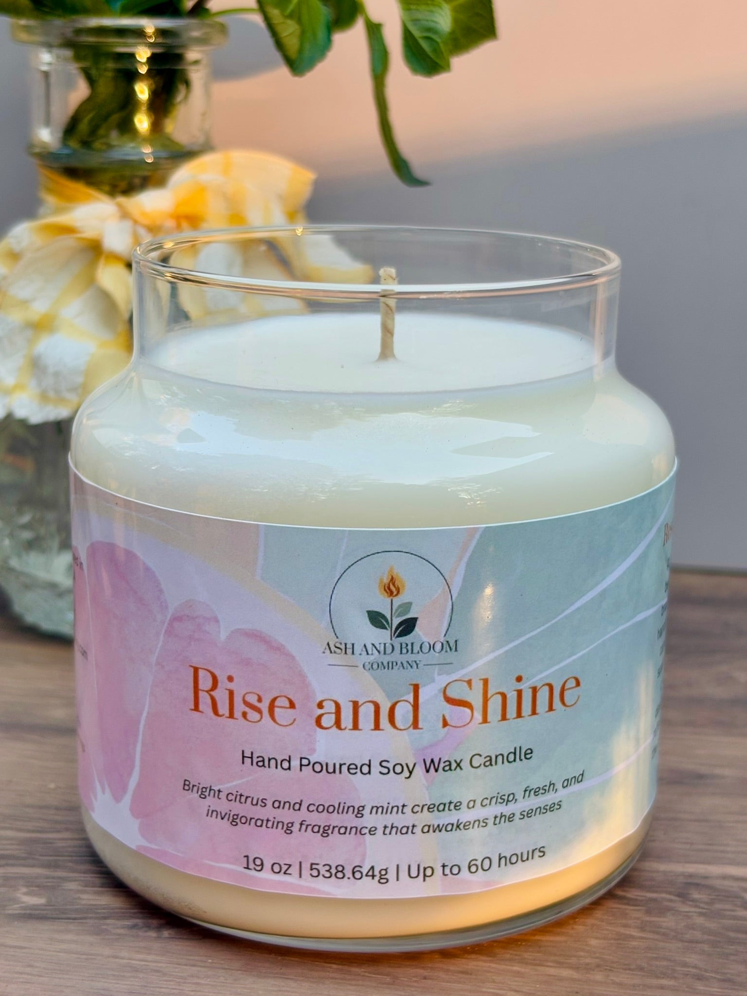 Citrus and mint candle with 'Rise and Shine' label on a wooden surface