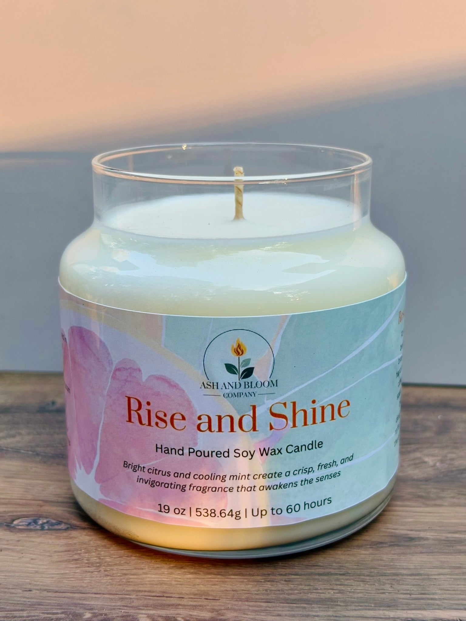 Citrus and mint candle in a glass jar with a label on a wooden surface