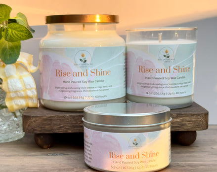 Three 'Rise and Shine' citrus and mint candles on a wooden stand with a soft background
