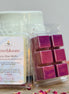 Lovebloom rose soy wax melts packaging with pinkish purple wax cubes on a wooden surface.