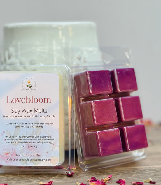 Lovebloom rose soy wax melts packaging with pinkish purple wax cubes on a wooden surface.