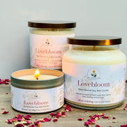 Lovebloom candles on a wooden surface with scattered rose petals.