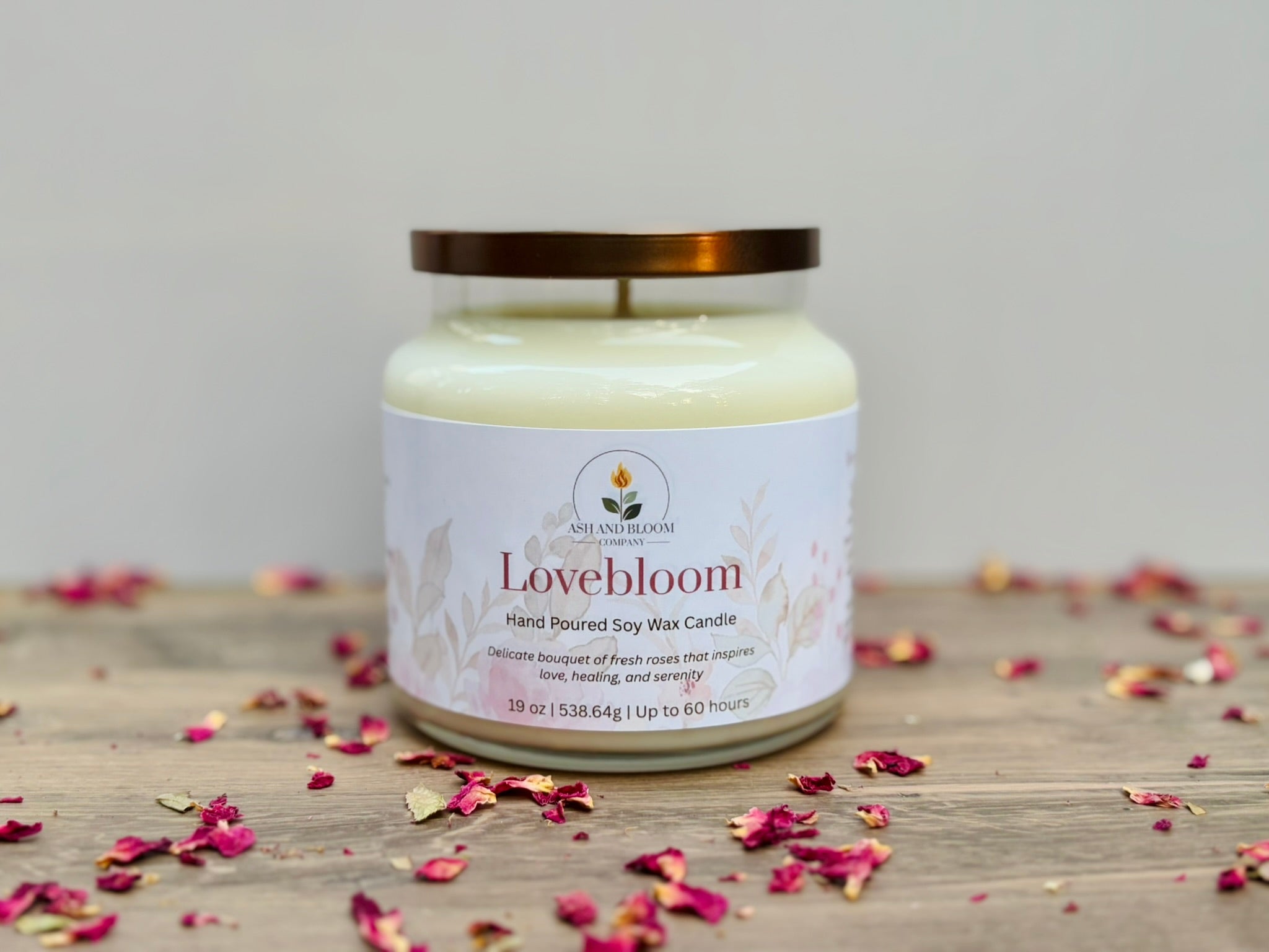 Lovebloom candle jar on a wooden surface with scattered dried flowers