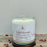 Lovebloom candle with a label on a wooden surface with dried flowers.