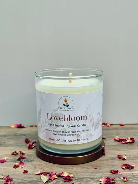 Lovebloom candle with a label on a wooden surface with dried flowers.