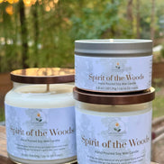 Two 'Spirit of the Woods' candles on a wooden surface with a blurred natural background