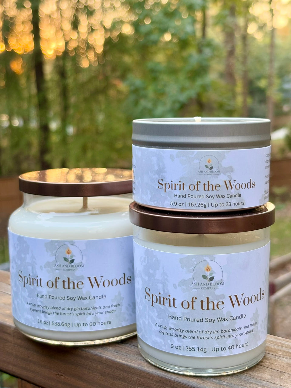 Two 'Spirit of the Woods' candles on a wooden surface with a blurred natural background