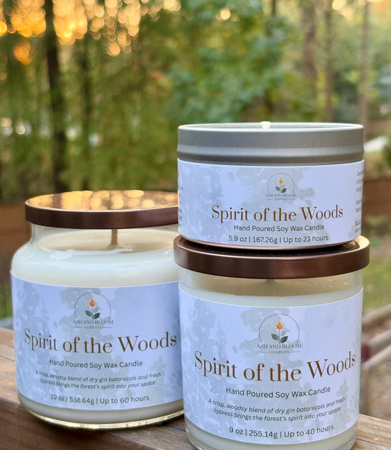 Two 'Spirit of the Woods' candles on a wooden surface with a blurred natural background