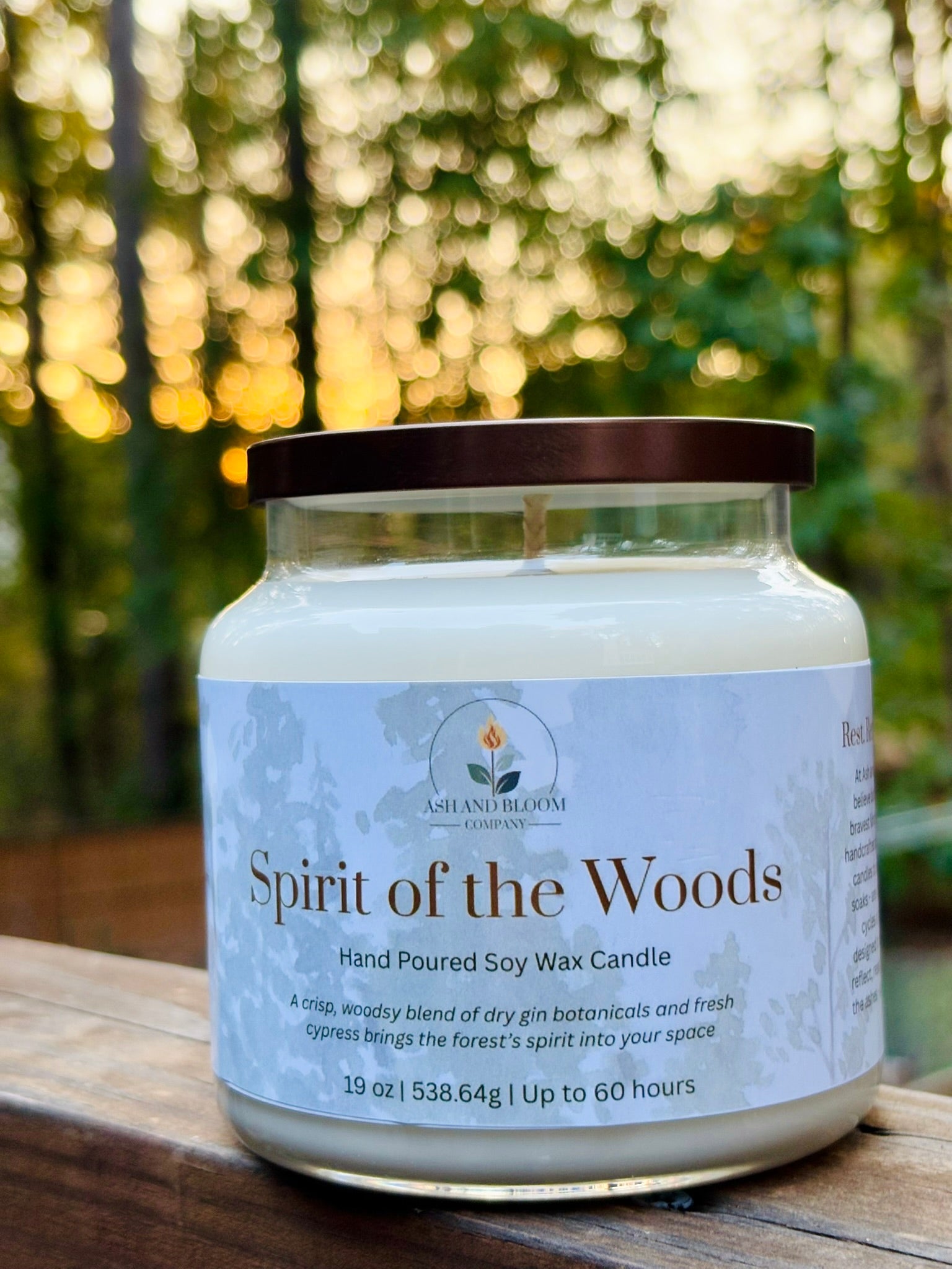 Candle labeled 'Spirit of the Woods' on a wooden surface with a blurred natural background