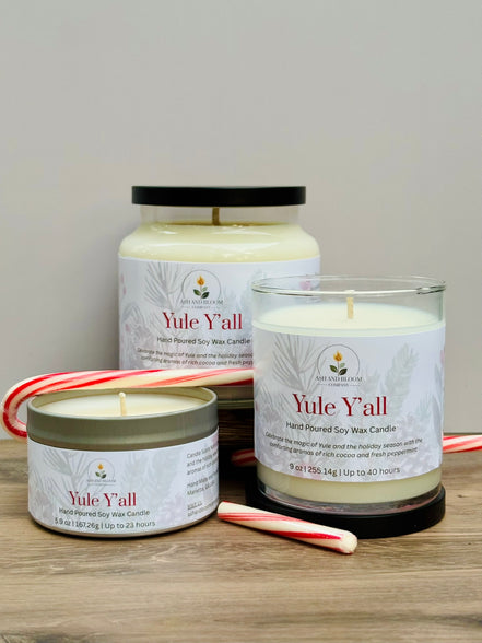 Three 'Yule Y'all' peppermint and chocolate candles of different sizes on a wooden surface with candy canes.