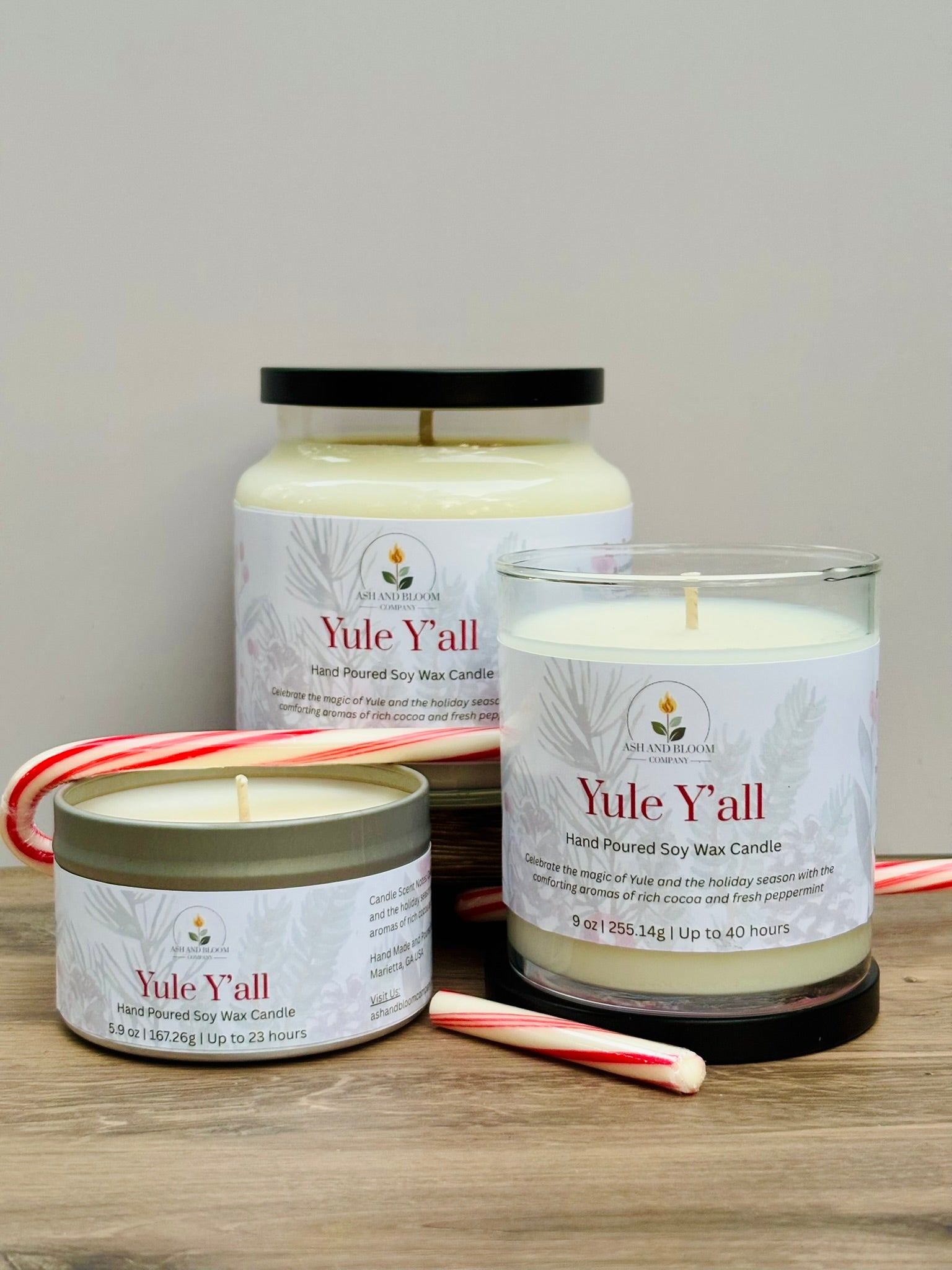 Three 'Yule Y'all' peppermint and chocolate candles of different sizes on a wooden surface with candy canes.
