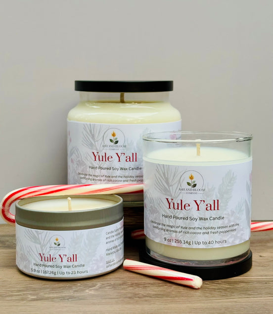 Three 'Yule Y'all' peppermint and chocolate candles of different sizes on a wooden surface with candy canes.