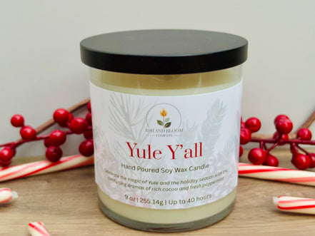 Candle jar labeled 'Yule Y'all' with holly and candy canes on a wooden surface.