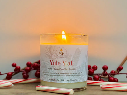 Peppermint and mocha candle labeled 'Yule Y'all' with candy canes and holly berries on a wooden surface.