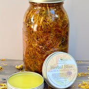 Jar of dried calendula flowers with a salve container labeled 'Herbal Bliss' on a wooden surface.
