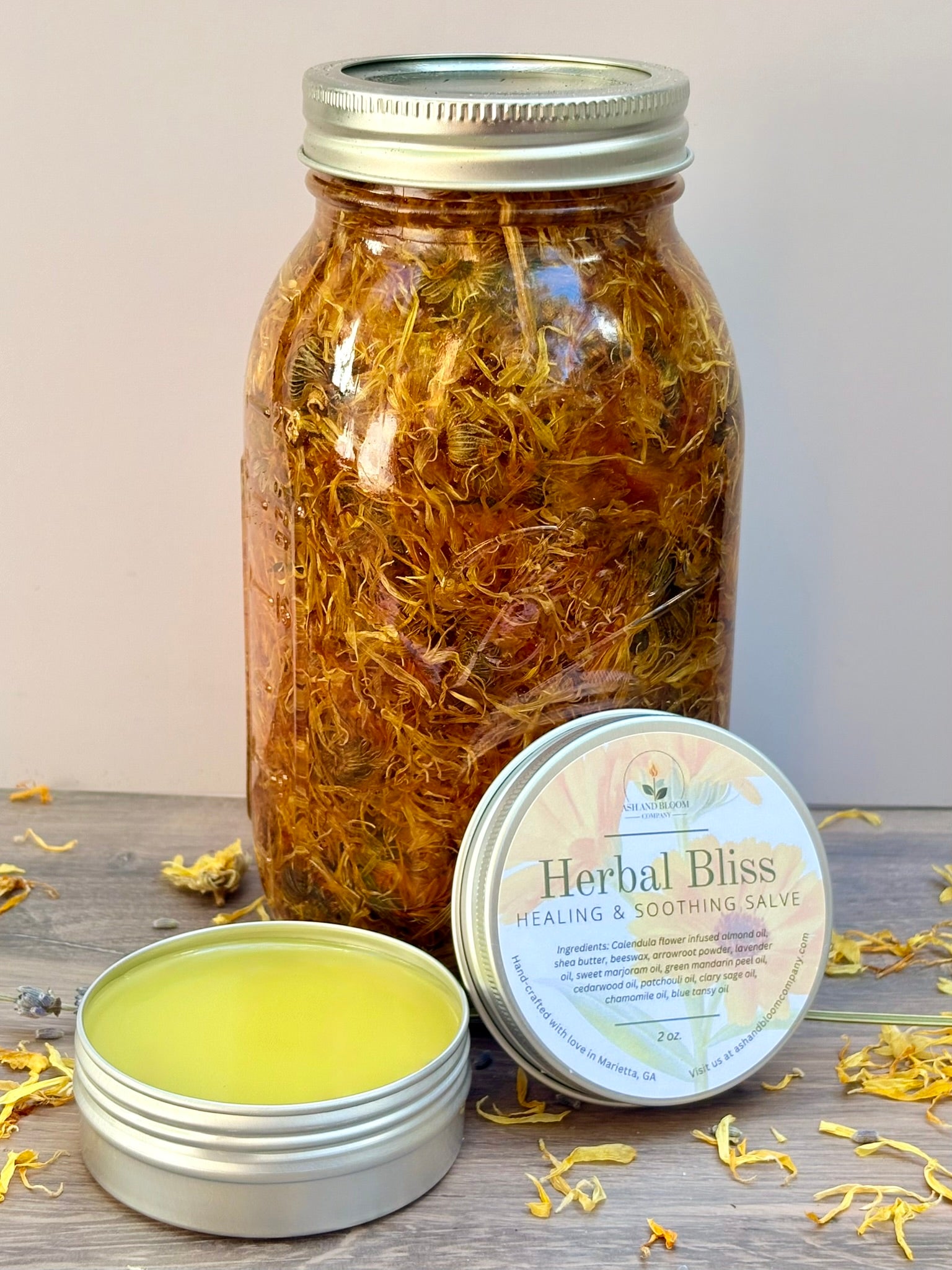 Jar of dried calendula flowers with a salve container labeled 'Herbal Bliss' on a wooden surface.