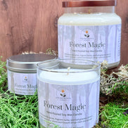 Three 'Forest Magic' candles on a wooden surface with grass.