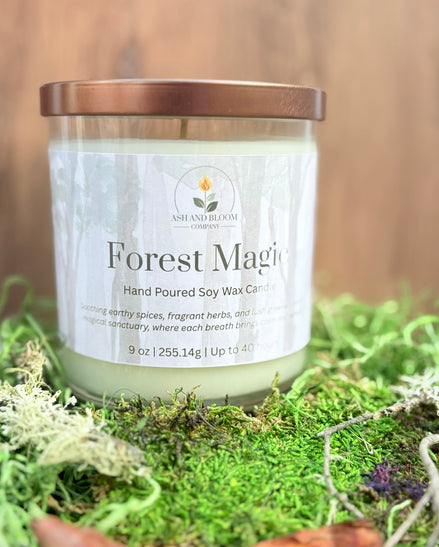 Candle labeled 'Forest Magic' on a bed of green moss with a blurred wooden background