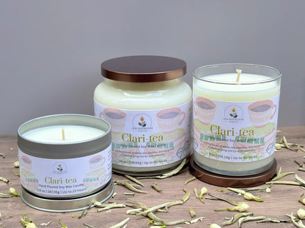 Three jasmine and white tea Clari Tea candles on a wooden surface with a gray background