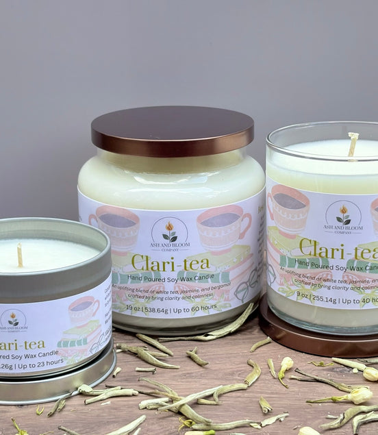 Three jasmine and white tea Clari Tea candles on a wooden surface with a gray background