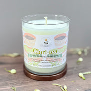 Candle labeled 'Clari-tea' on a wooden surface with a neutral background