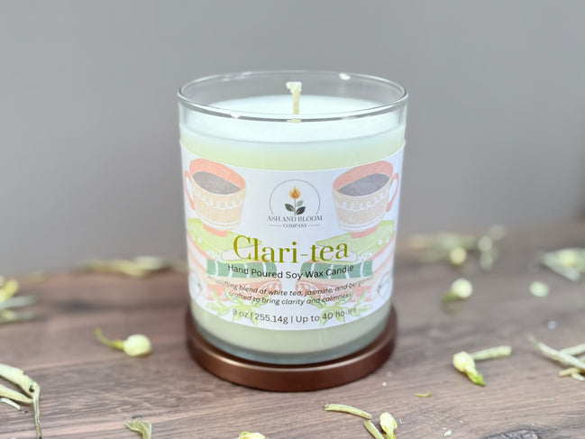Candle labeled 'Clari-tea' on a wooden surface with a neutral background