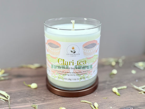 Candle labeled 'Clari-tea' on a wooden surface with a neutral background