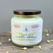 Jar of 'Clari Tea' candle with a decorative label on a wooden surface.