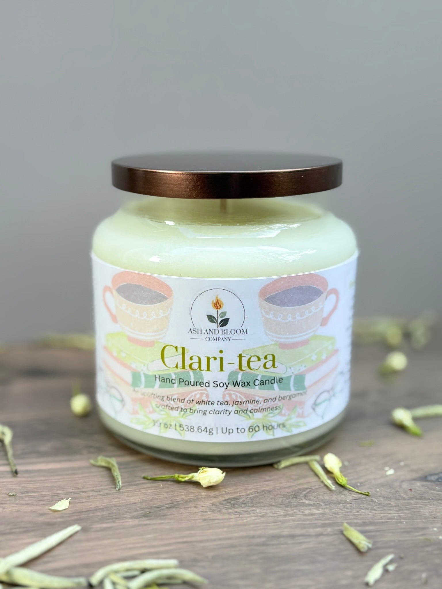 Jar of 'Clari Tea' candle with a decorative label on a wooden surface.