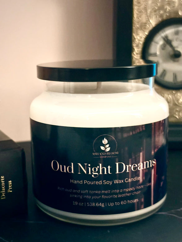 Jar of 'Oud Night Dreams' candle with a dark label on a surface.