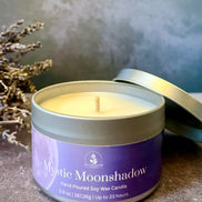 Mystic Moonshadow candle in a tin with lavender branches on a textured surface