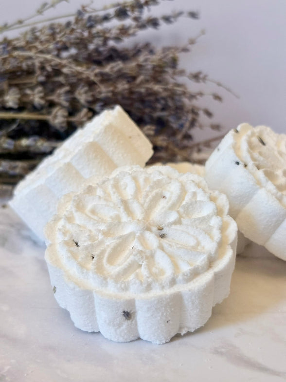 Decorative shower steamer with intricate design on a light surface with lavender in the background